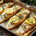 Pan-seared steelhead trout fillet with crispy golden skin, garnished with fresh herbs and lemon, served on a rustic plate